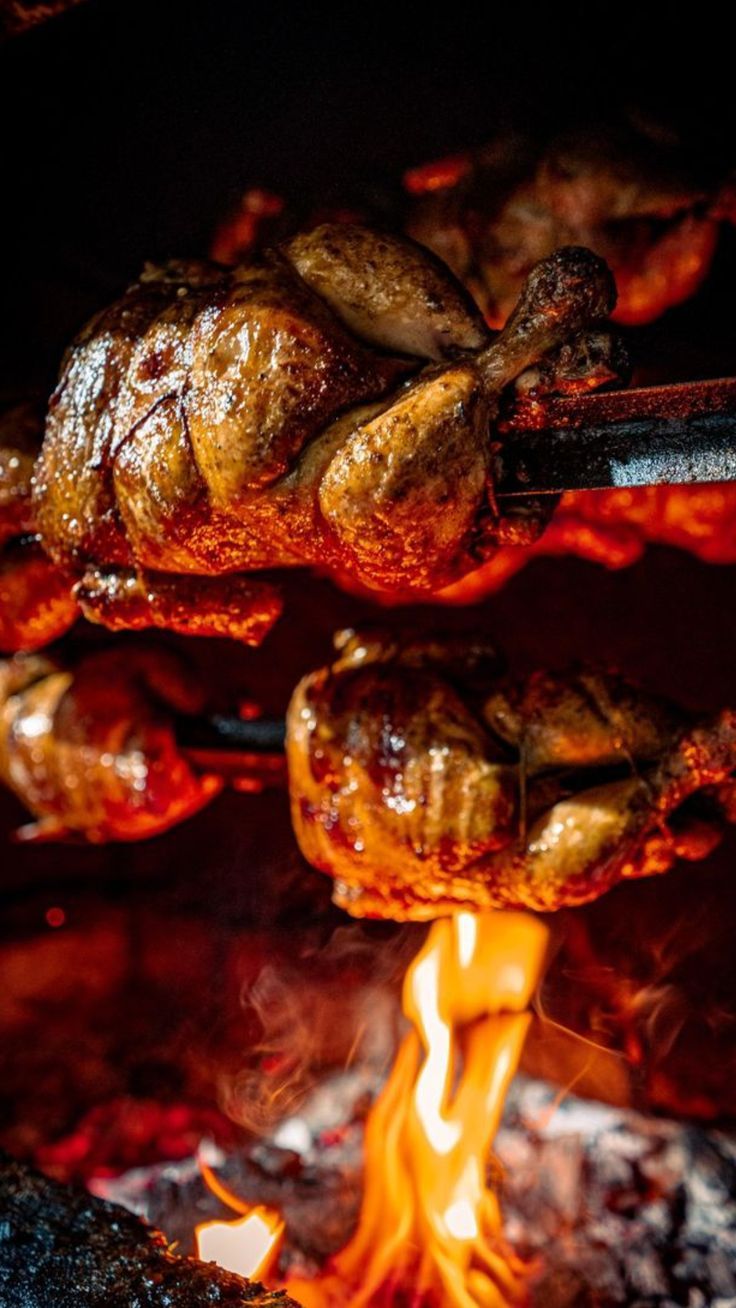 Pollos a la brasa dorándose sobre las brasas en Parrillín